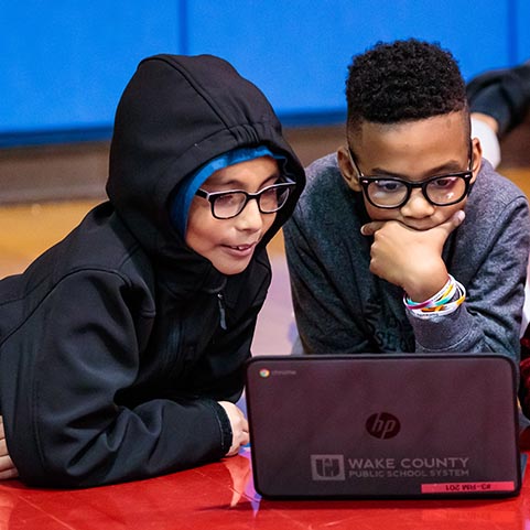  two boys looking at a laptop